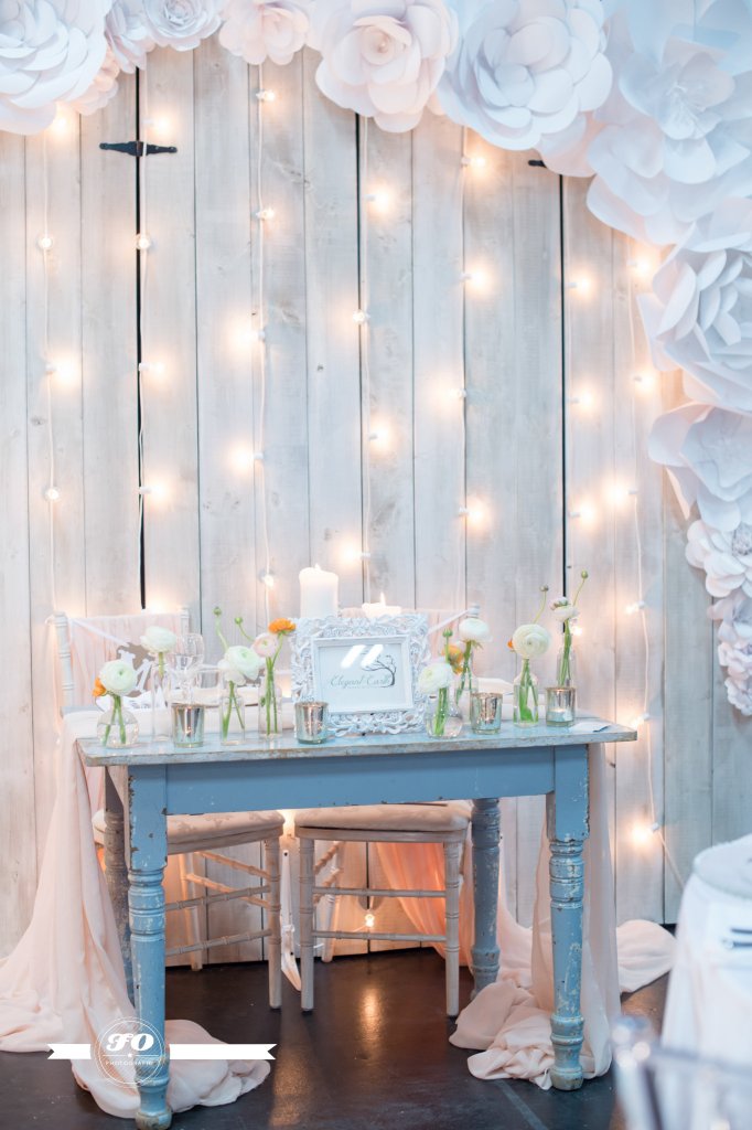 White-washed barn wood, framed by paper flowers, and dripping with lights and romance.
