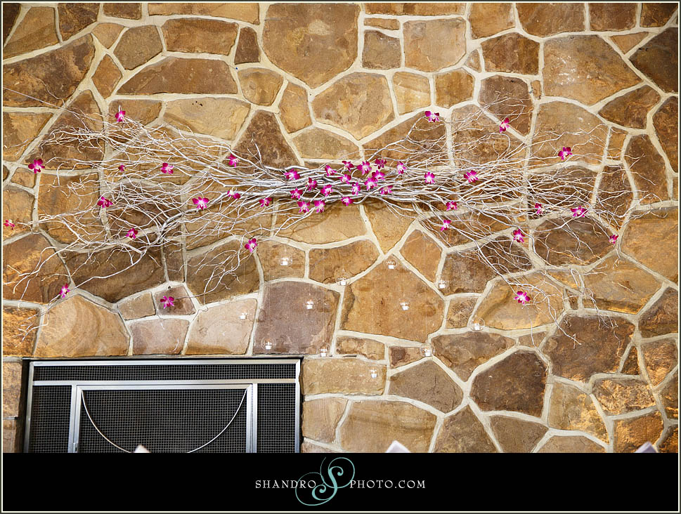 The Royal Glenora features a rock fireplace that worked as a great backdrop for Vanessa & Cody's head table. We amped up the glamour with a custom willow branch wall piece adorned fuschia orchids and hanging glass bulbs containing tea lights